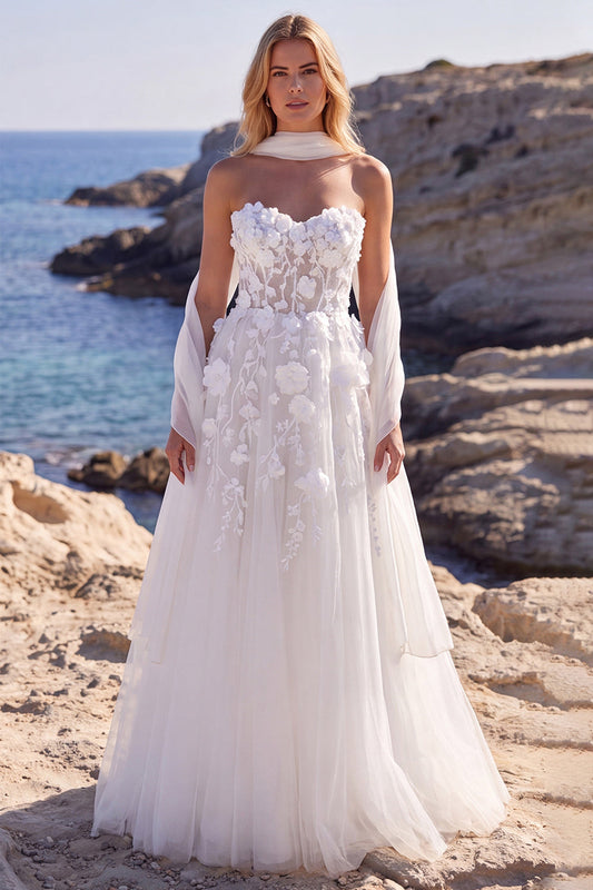 Robe de mariée longue blanche en tulle coupe évasée, ornée de fleurs, corsage cœur et appliqués