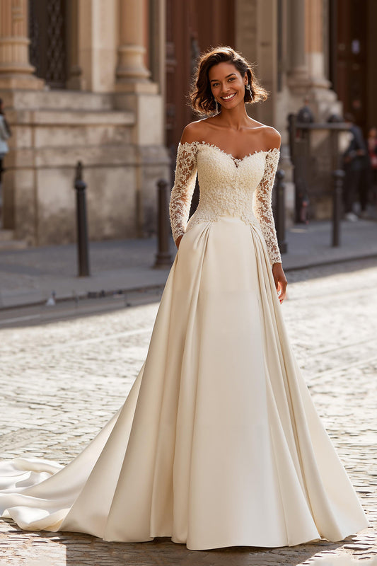 Robe de mariée ivoire avec applique de dentelle, coupe trapèze, épaules dénudées et traîne balayage.
