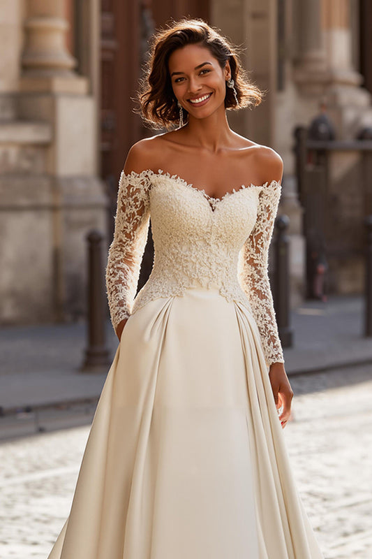 Robe de mariée ivoire avec applique de dentelle, coupe trapèze, épaules dénudées et traîne balayage.