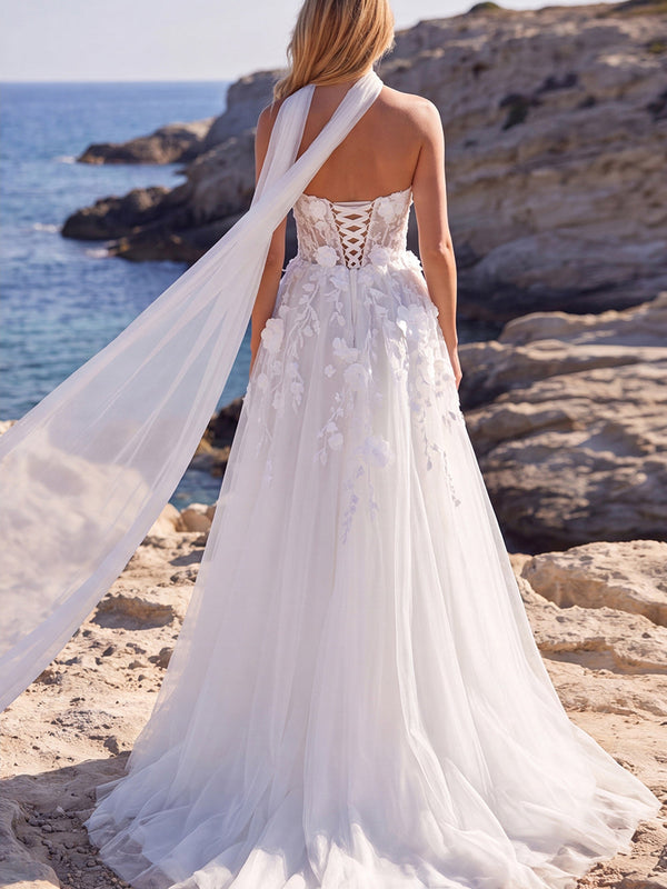 Robe de mariée longue blanche en tulle coupe évasée, ornée de fleurs, corsage cœur et appliqués